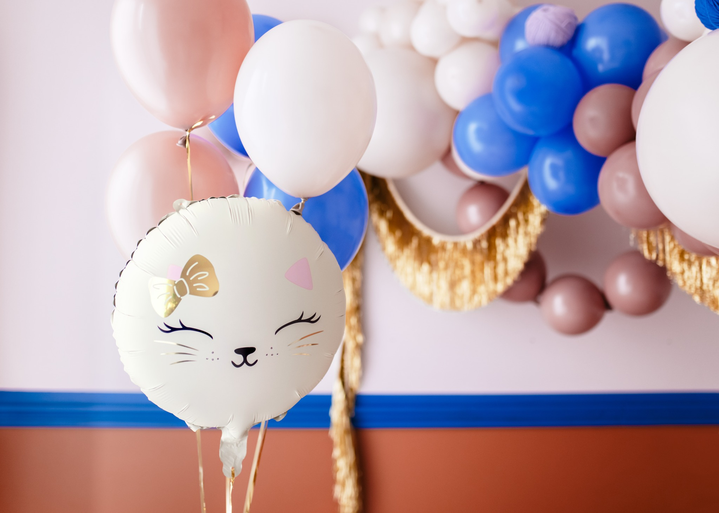 Cute cat face foil balloon with gold bow and whiskers, perfect for a kitty-themed birthday party or celebration.