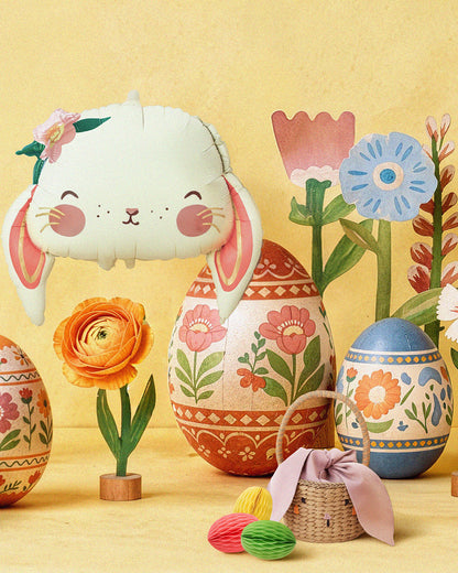 Decorative Easter scene with a bunny-shaped balloon, floral eggs, and flowers on a yellow background.