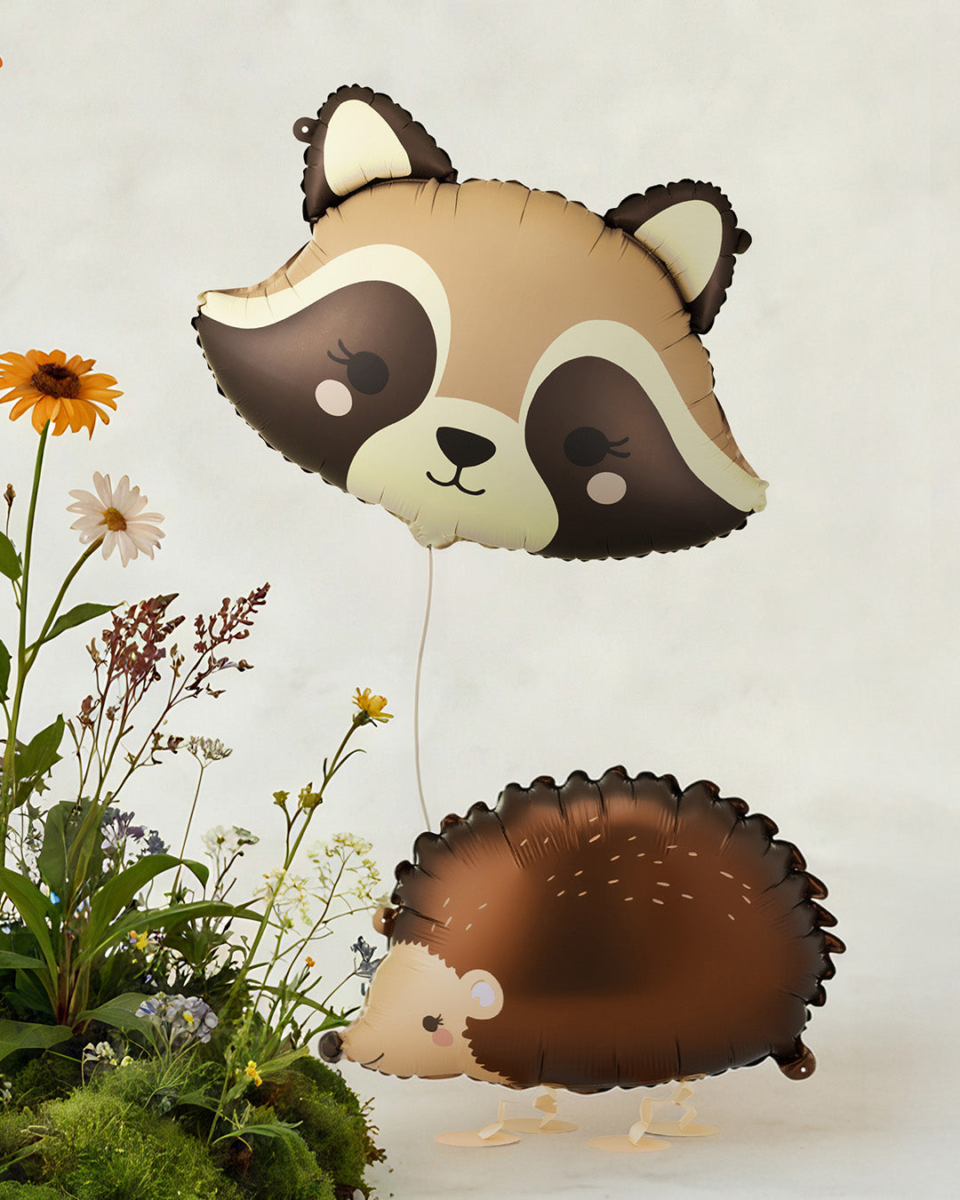 Raccoon and hedgehog-shaped balloons with flowers on a light background
