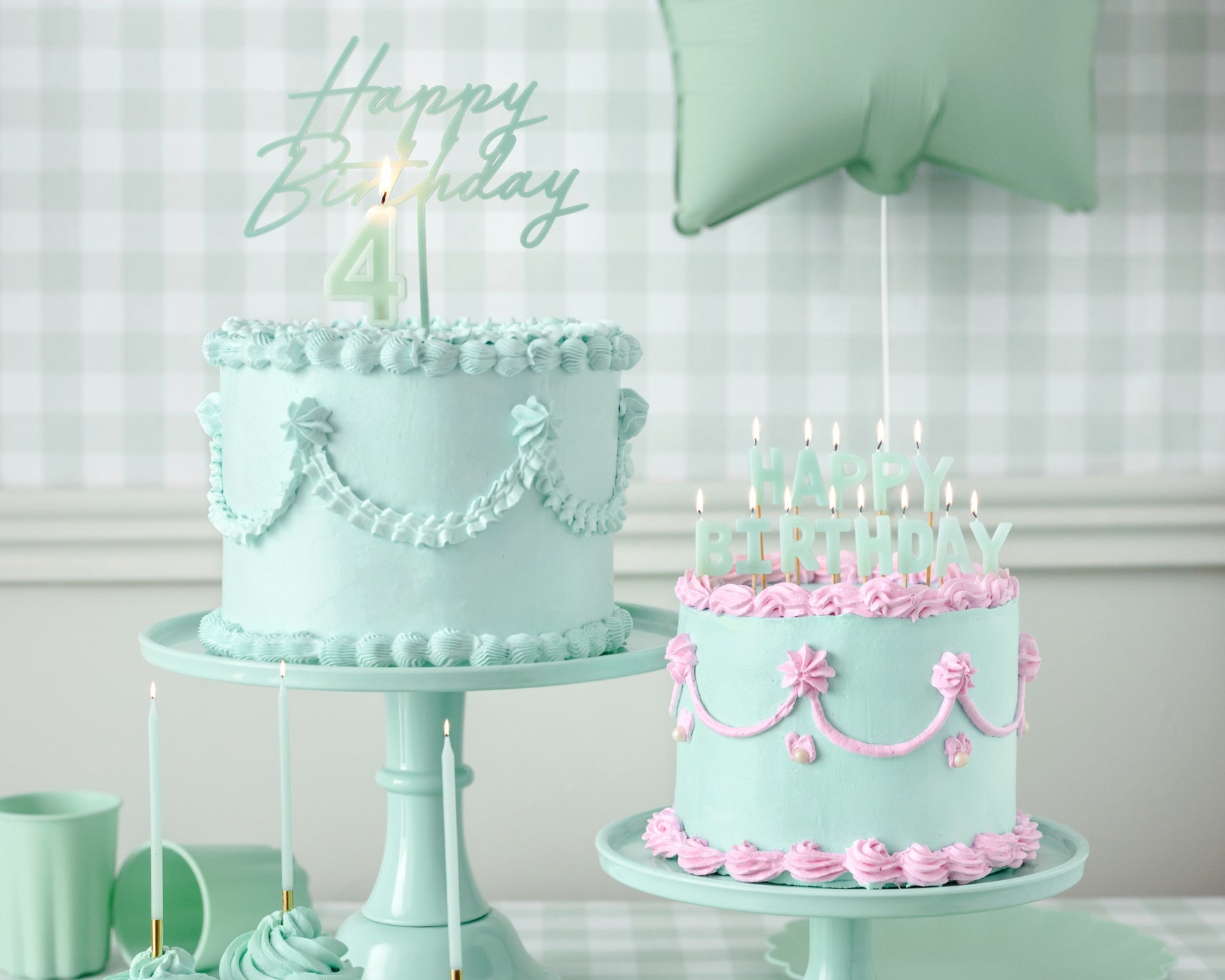Two, mint birthday cakes with candles and toppers