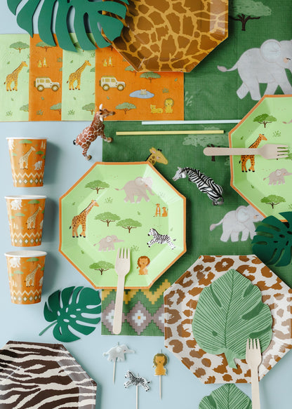 Children's party tableware with safari-themed design on plates, cups, and cutlery.