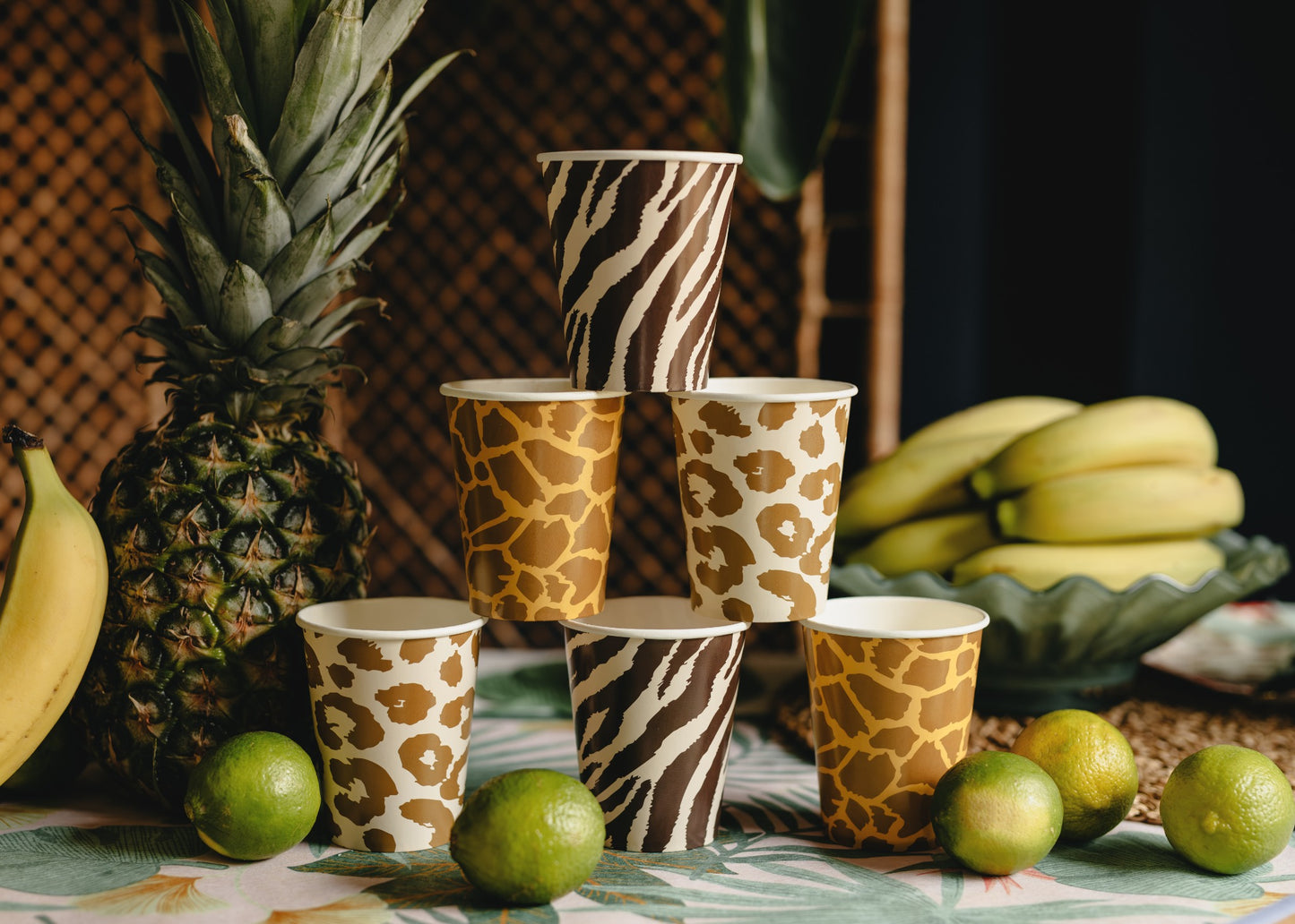 Cups with animal print designs on a table with fruits