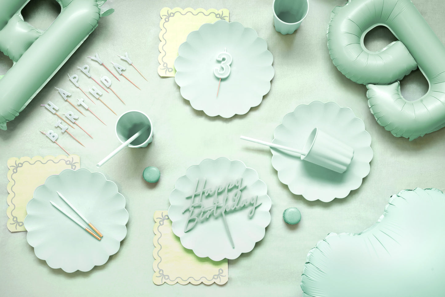 Mint green party supplies including plates, cups, and balloons on a light background