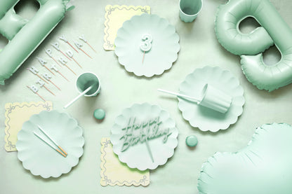 Mint green party supplies including plates, cups, and balloons on a light background