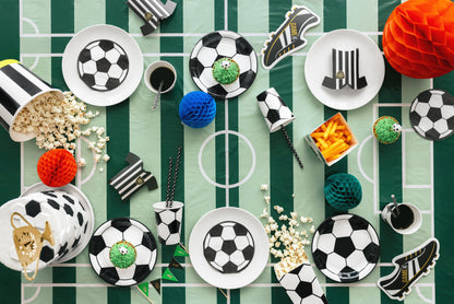 Decorative items including soccer-themed plates, balls, and shoes on a green and white striped background.