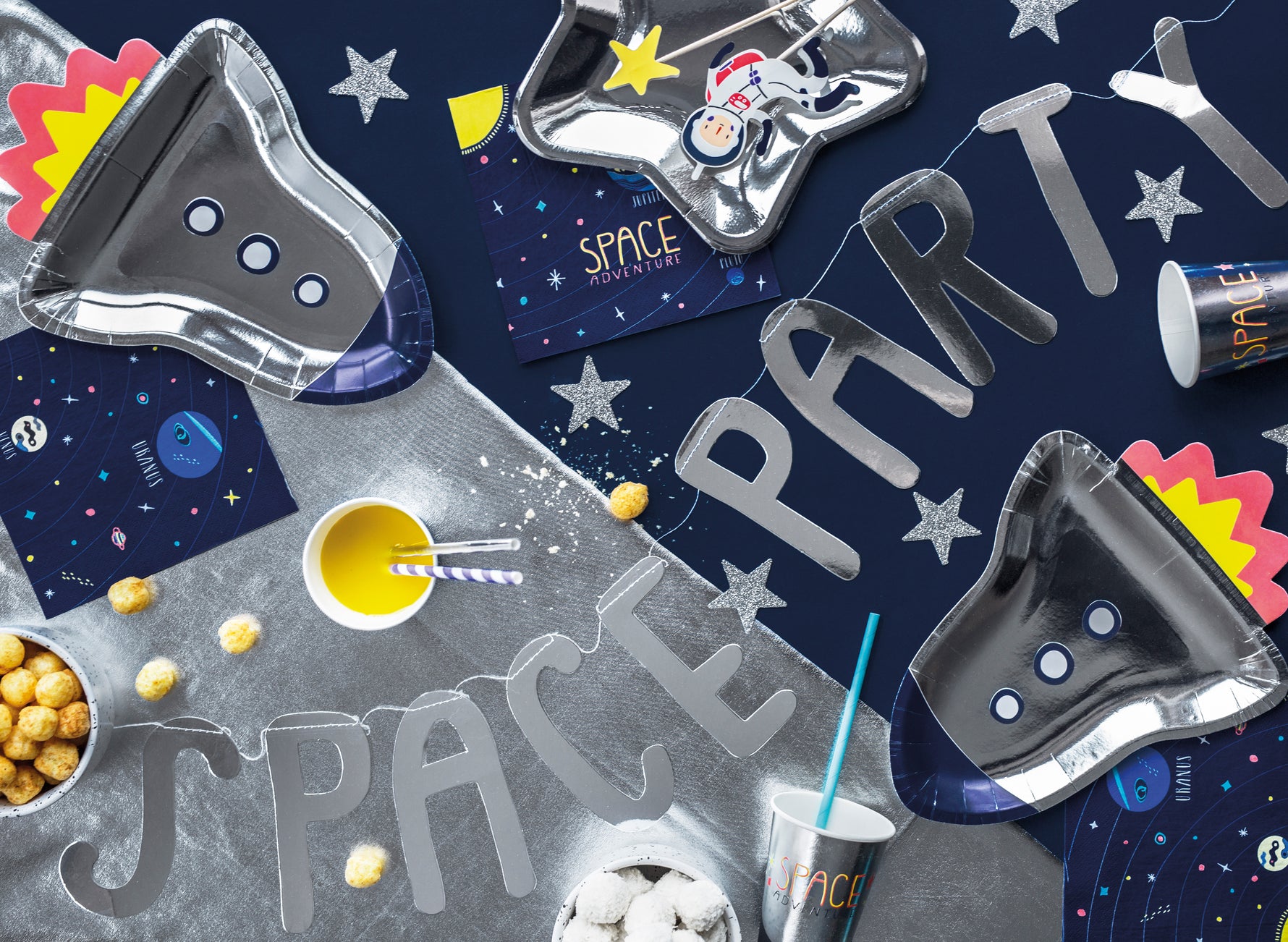 Space-themed party supplies including cups, plates, and decorations such as banner