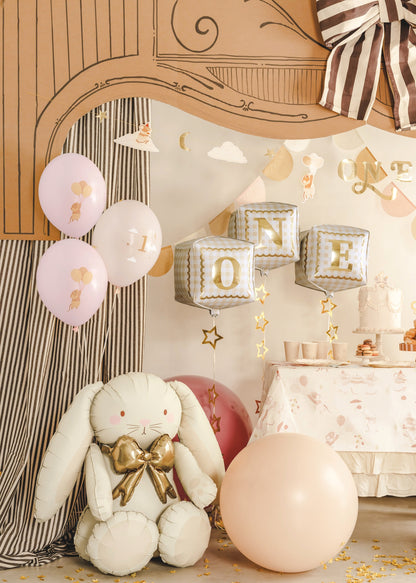 Decorative setting with balloons, a plush bunny, and 'ONE' balloons for a first birthday celebration.