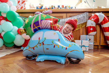 Child playing with a large inflatable Christmas sleigh in a festive room.