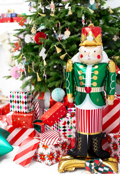 Decorative nutcracker figure in front of a Christmas tree with presents.