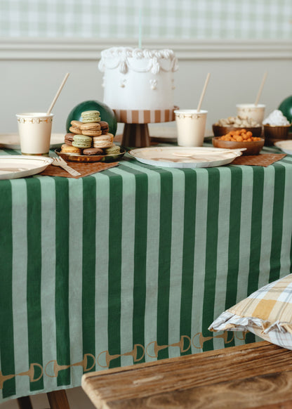 Table setting with a green and white striped tablecloth, plates, and a cake.