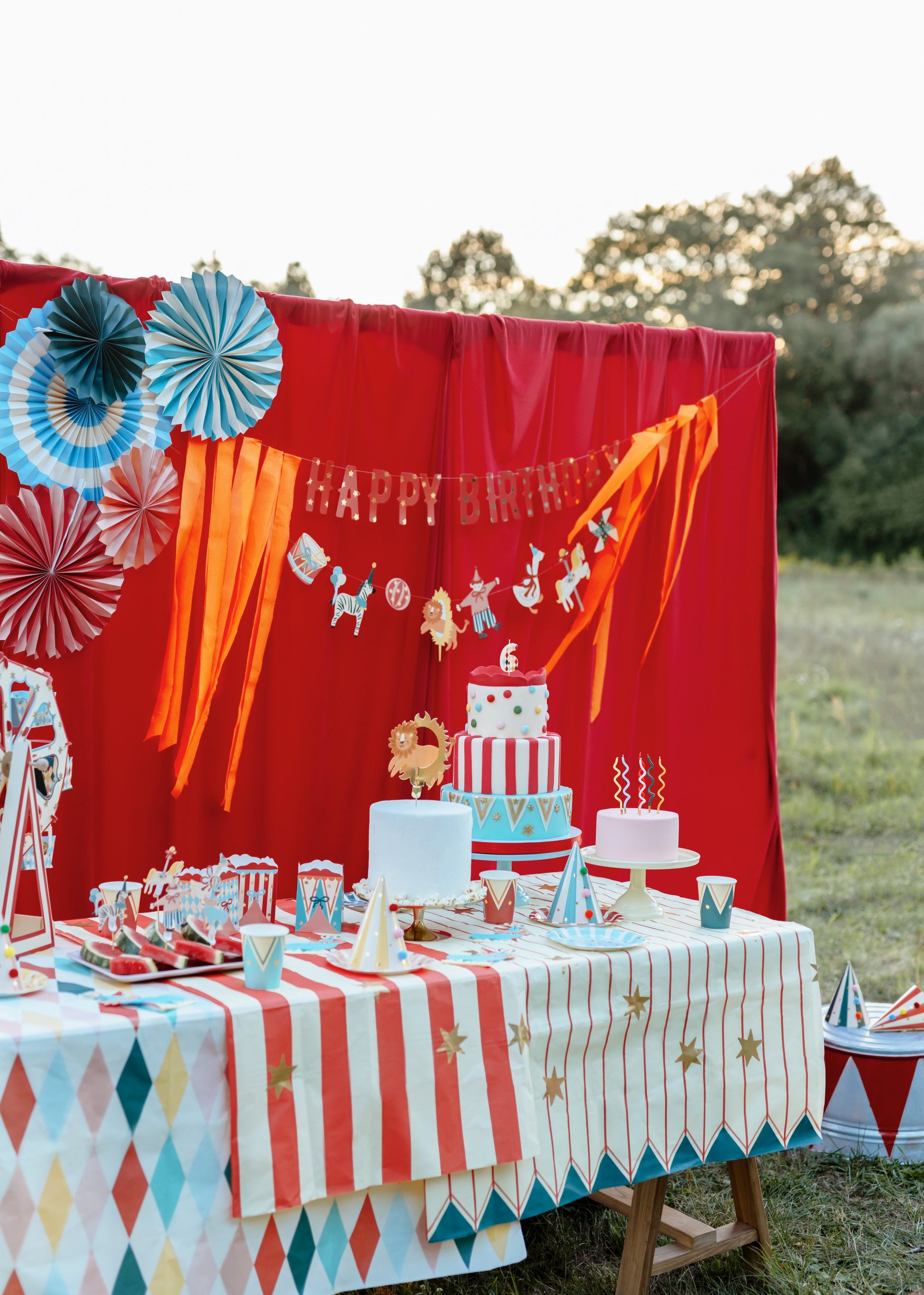 Magic Circus birthday party setup with a red backdrop, cake, and decorations.