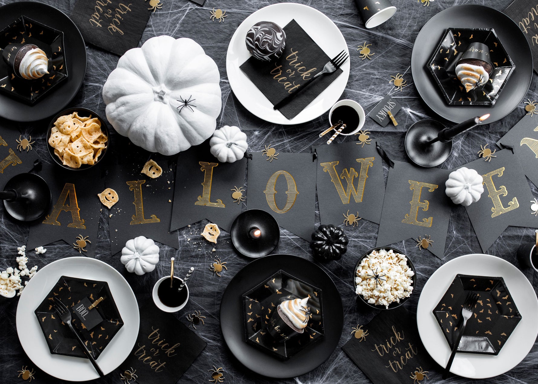 Halloween-themed table setting with black and gold decorations on a dark surface.
