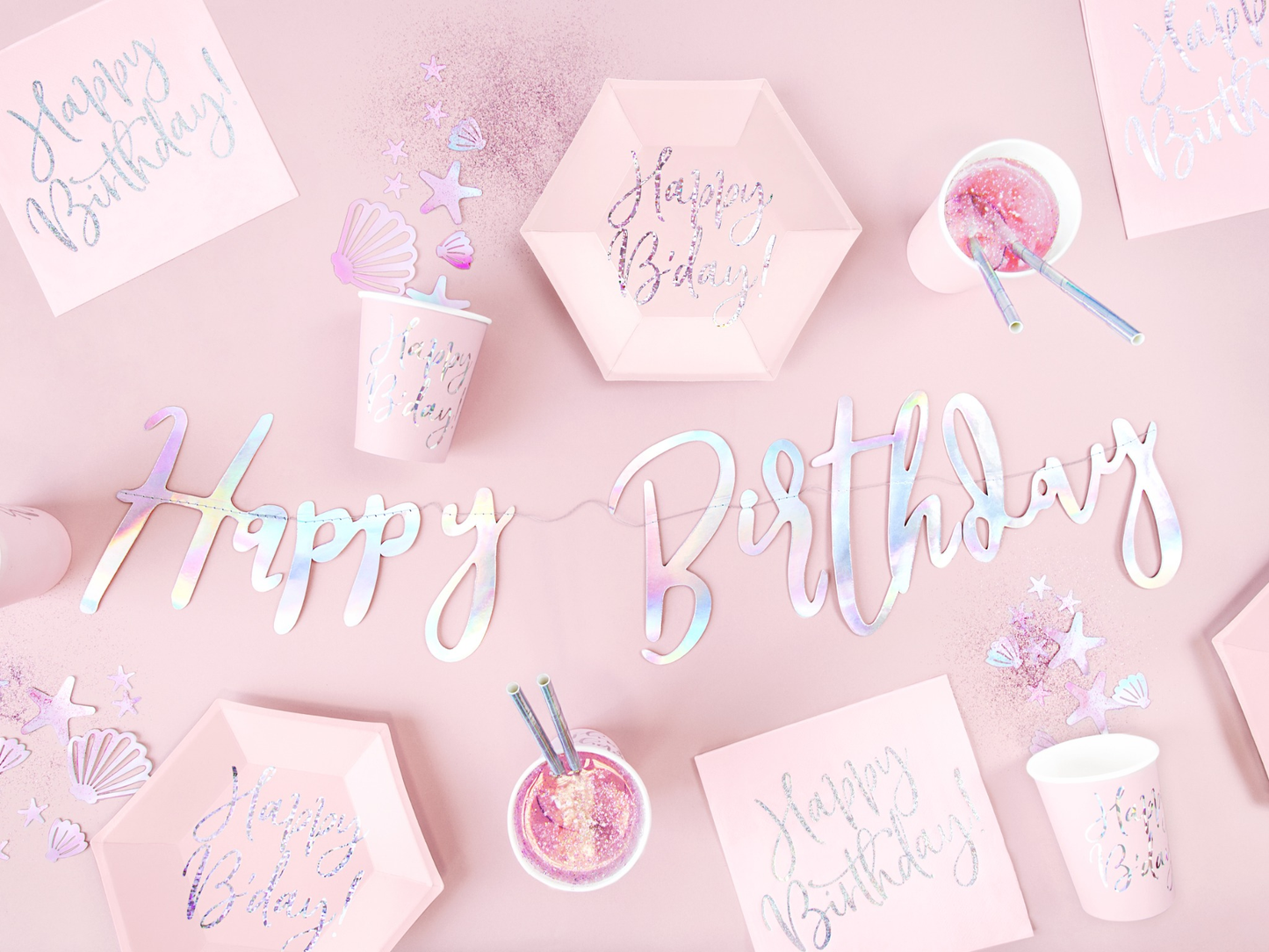 Pink mermaid birthday party tableware set with iridescent 'Happy Birthday' banner, pastel cups, plates, napkins, and ocean-themed confetti – magical under the sea party deco