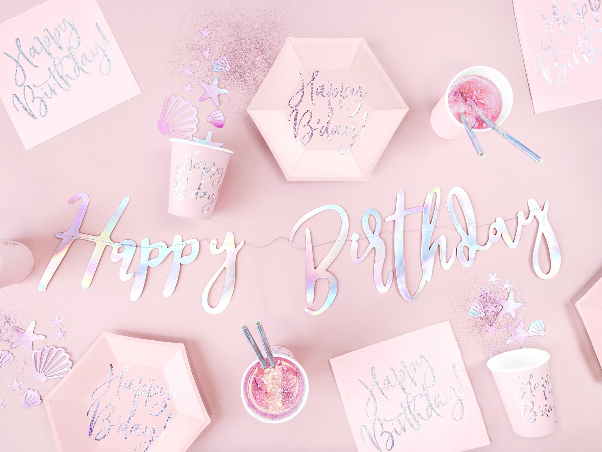 Pink mermaid birthday party tableware set with iridescent 'Happy Birthday' banner, pastel cups, plates, napkins, and ocean-themed confetti – magical under the sea party deco