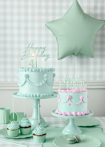 Mint green birthday party decor with star balloon, pastel cakes, pink icing details, and coordinated cupcakes and tableware