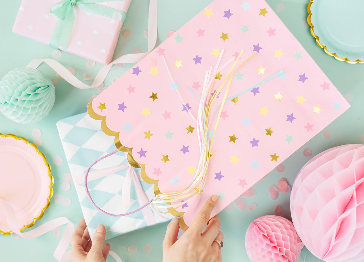 Pink gift bag with pastel stars and ribbons – unicorn-themed party favor bag