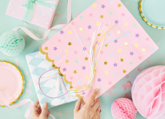 Pink gift bag with pastel stars and ribbons – unicorn-themed party favor bag