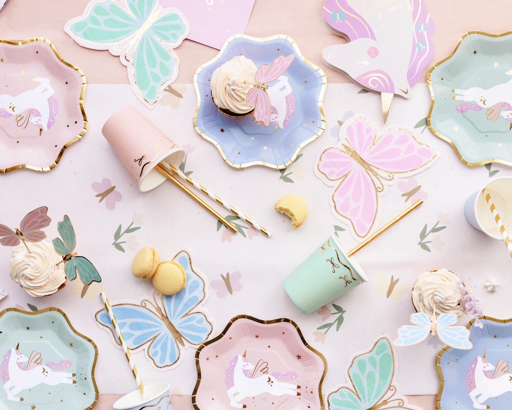 Pastel-colored paper plates with unicorn designs, gold straws and colorful cups