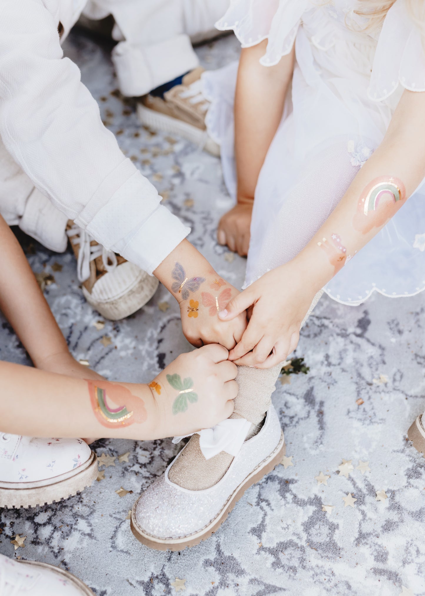 Two pairs of hands with unicorn temporary tattoos  holding each other on a textured surface