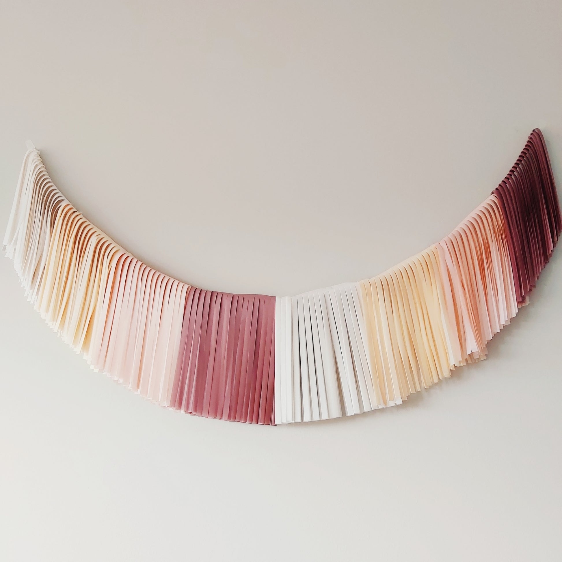 Decorative tassel with pleated fabric in gradient colors on a plain background