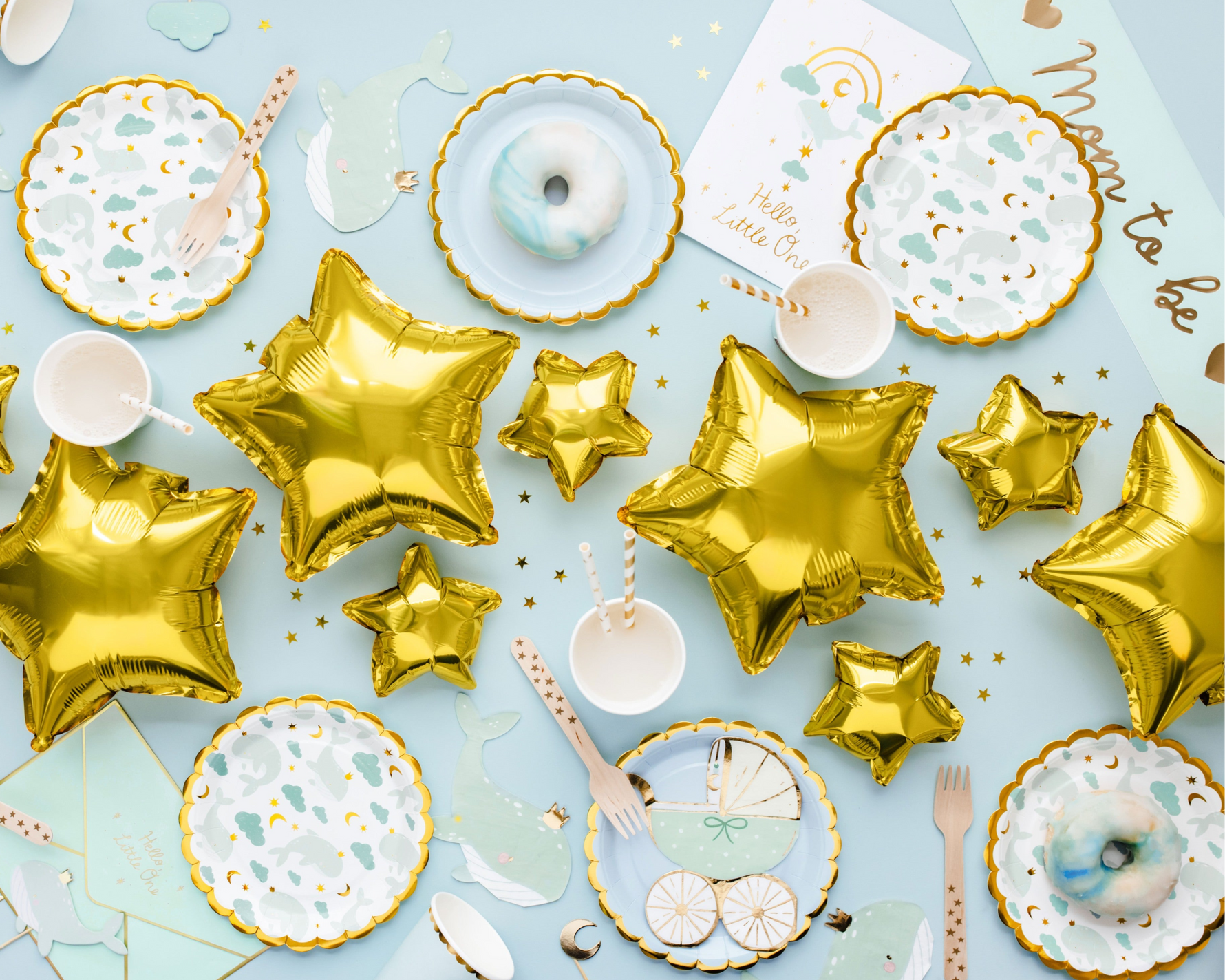 Table setting with gold star balloons, plates and wooden cutlery.