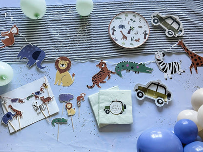 Children's party decorations with animal-themed paper plates, napkins, and balloons on a striped tablecloth.