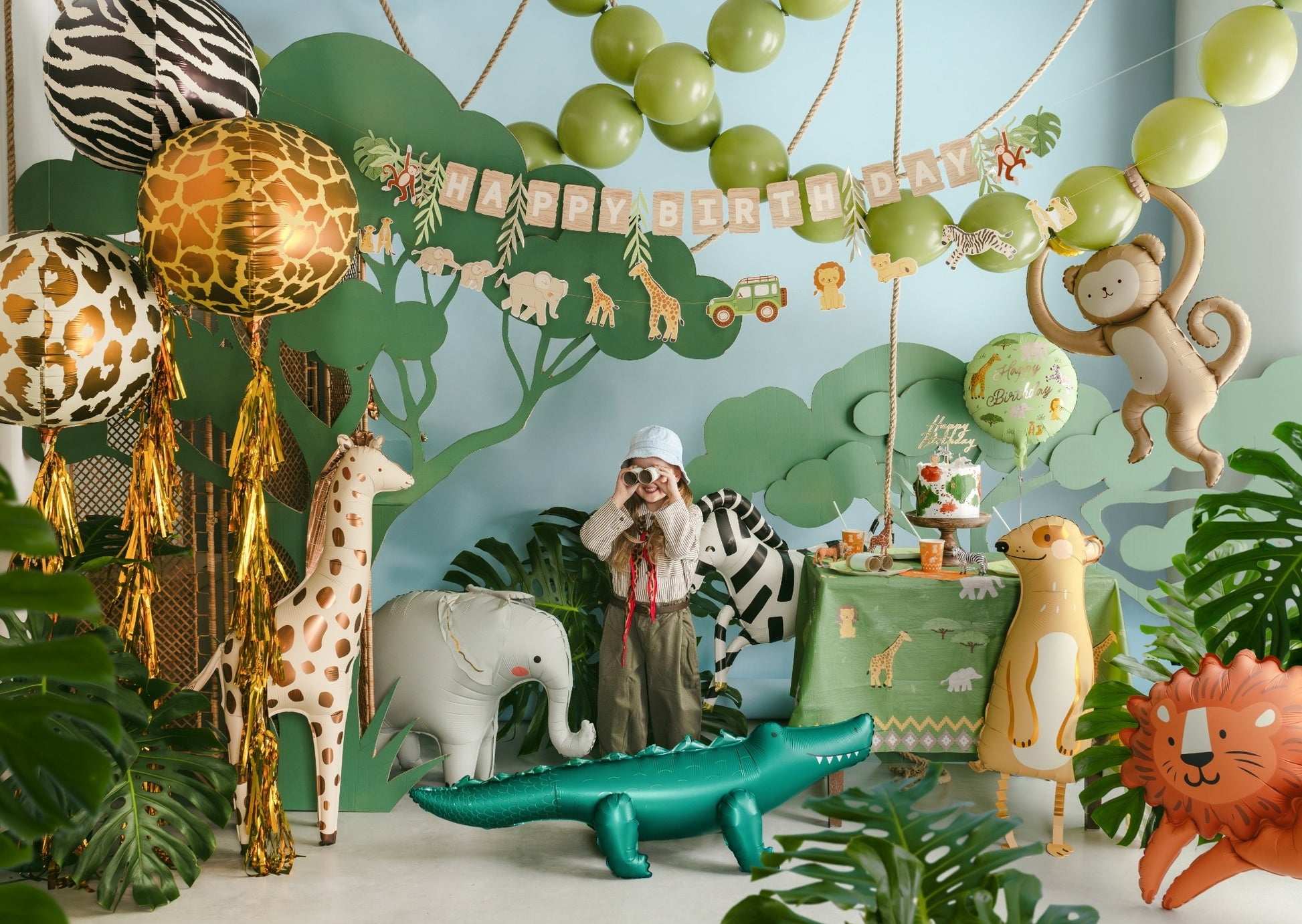 Jungle-themed birthday party with decorations, balloons, and animal figurines.