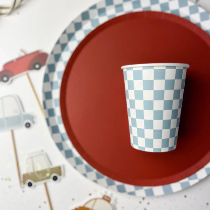 Checkered paper cup on a red plate with decorative elements in the background