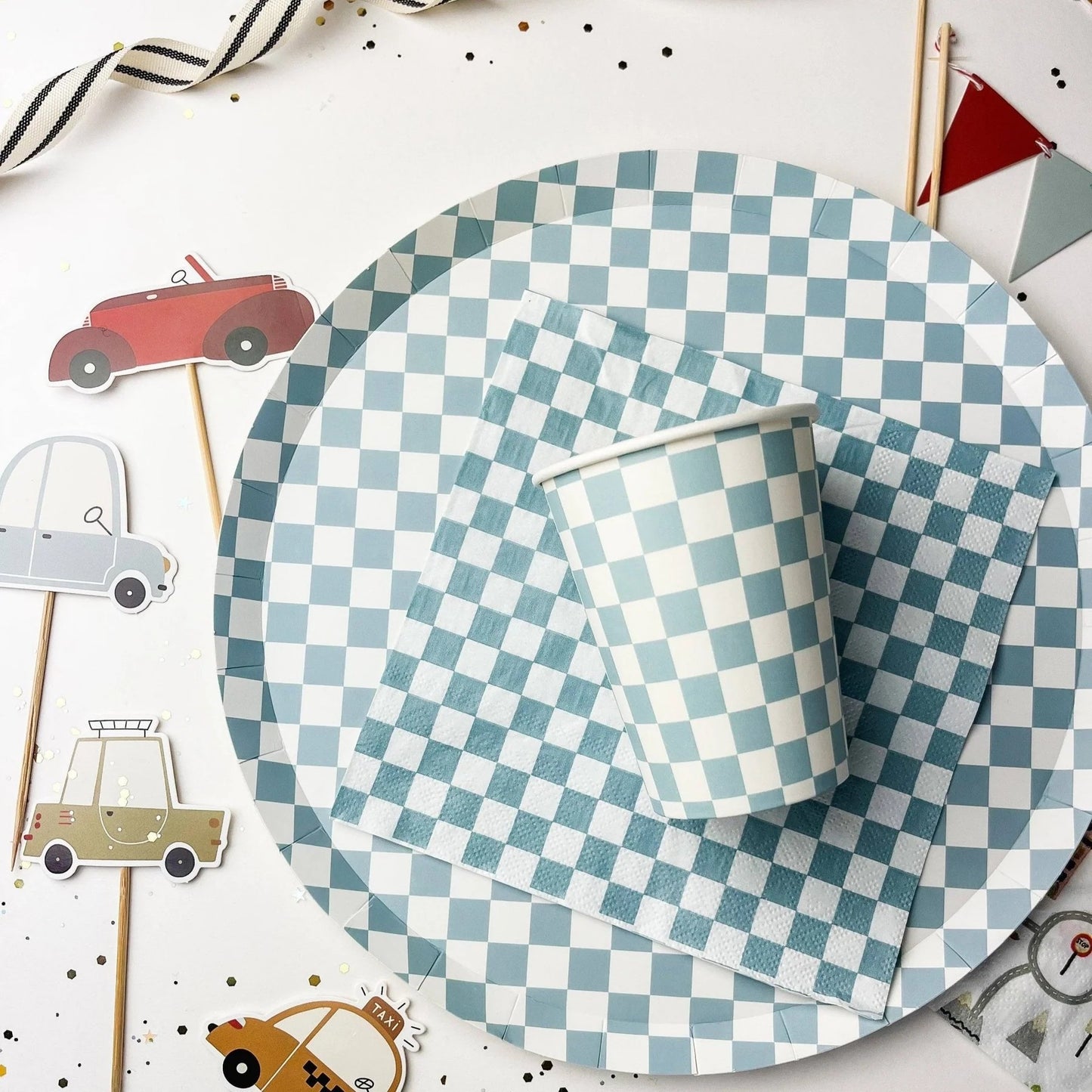Checkered paper plate and cup on a white background with small car decorations.