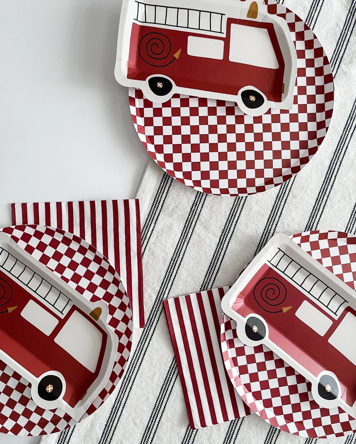 Fire truck-themed paper plates with red and white checkered design on a striped background