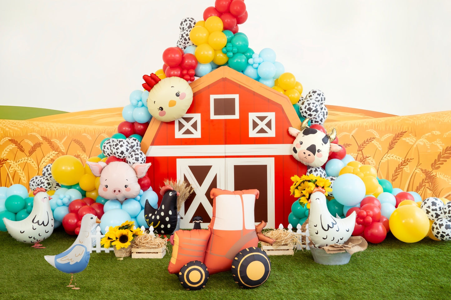 Colorful barn-themed birthday party setup with balloons, toys, and a toy tractor.