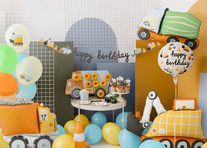 Birthday party setup with balloons, cake, and decorative elements on a table.