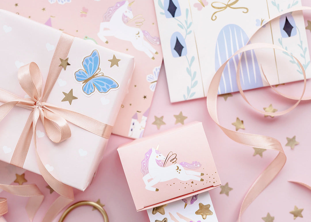 Decorative envelopes with stickers, ribbons, and a pair of scissors on a pink background
