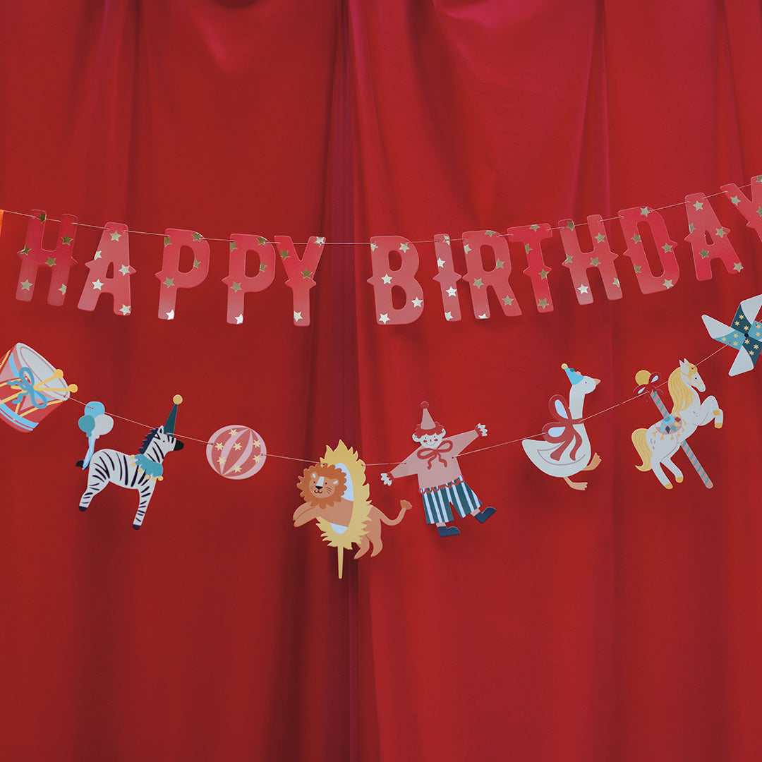 Happy Birthday banner with circus-themed decorations on a red background