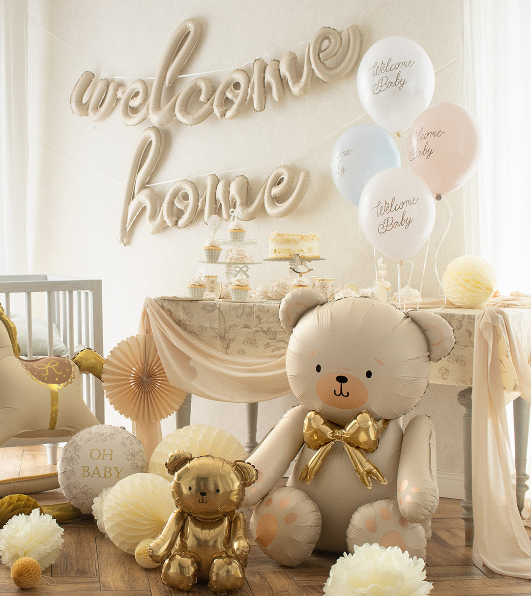 Baby shower setup with teddy bear decorations, balloons, and a 'welcome home' foil balloon.