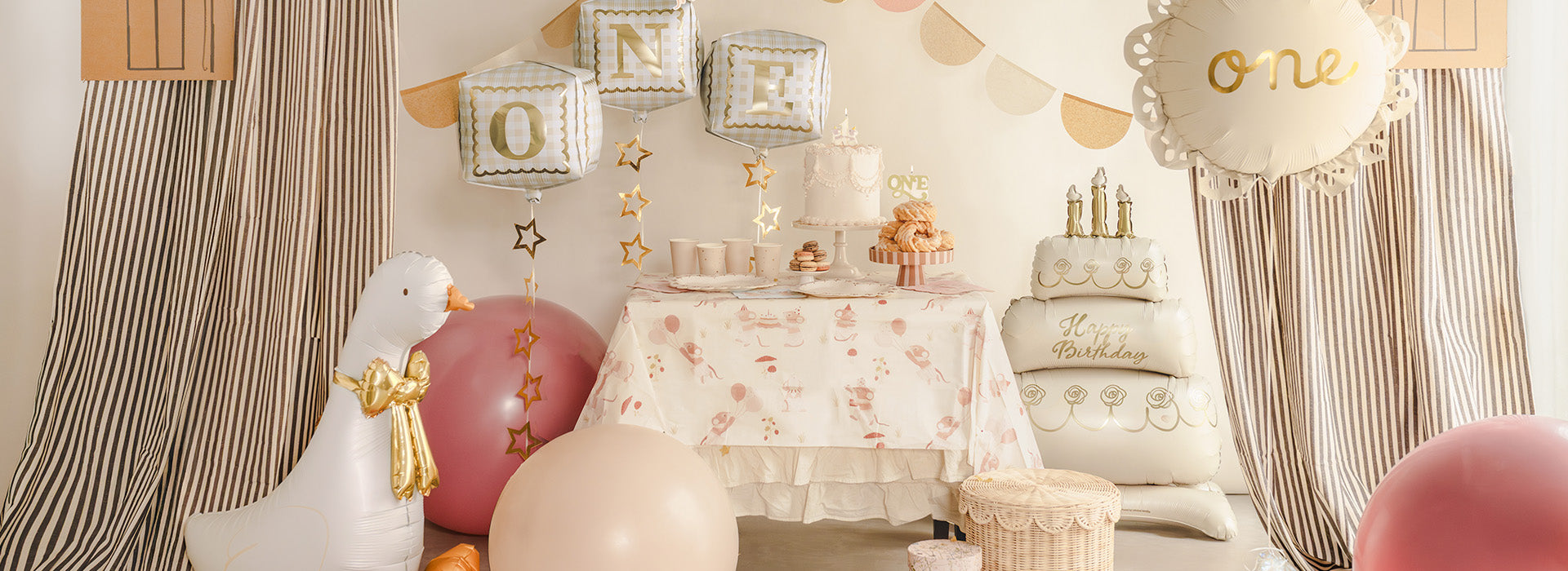 Decorative setup for first birthday with balloons  such as a cake and a goose n beige shades.