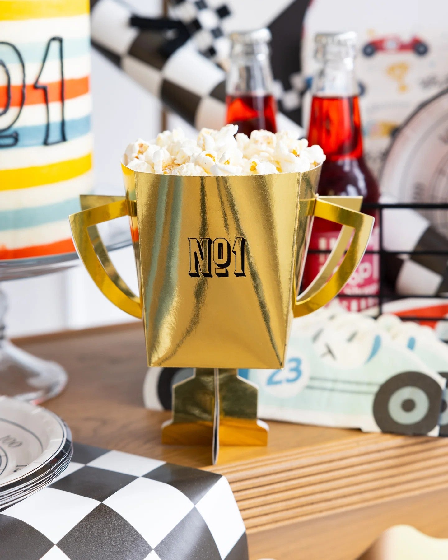 Gold trophy-shaped popcorn bucket with 'No.1' on a checkered surface