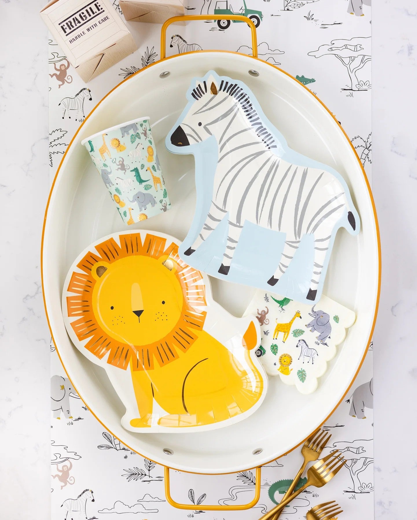 Children's tableware set with lion, zebra, and giraffe designs on a white plate with gold rim.