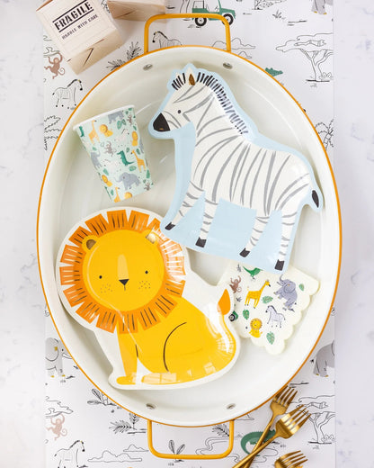 Children's tableware set with lion, zebra, and giraffe designs on a white plate with gold rim.
