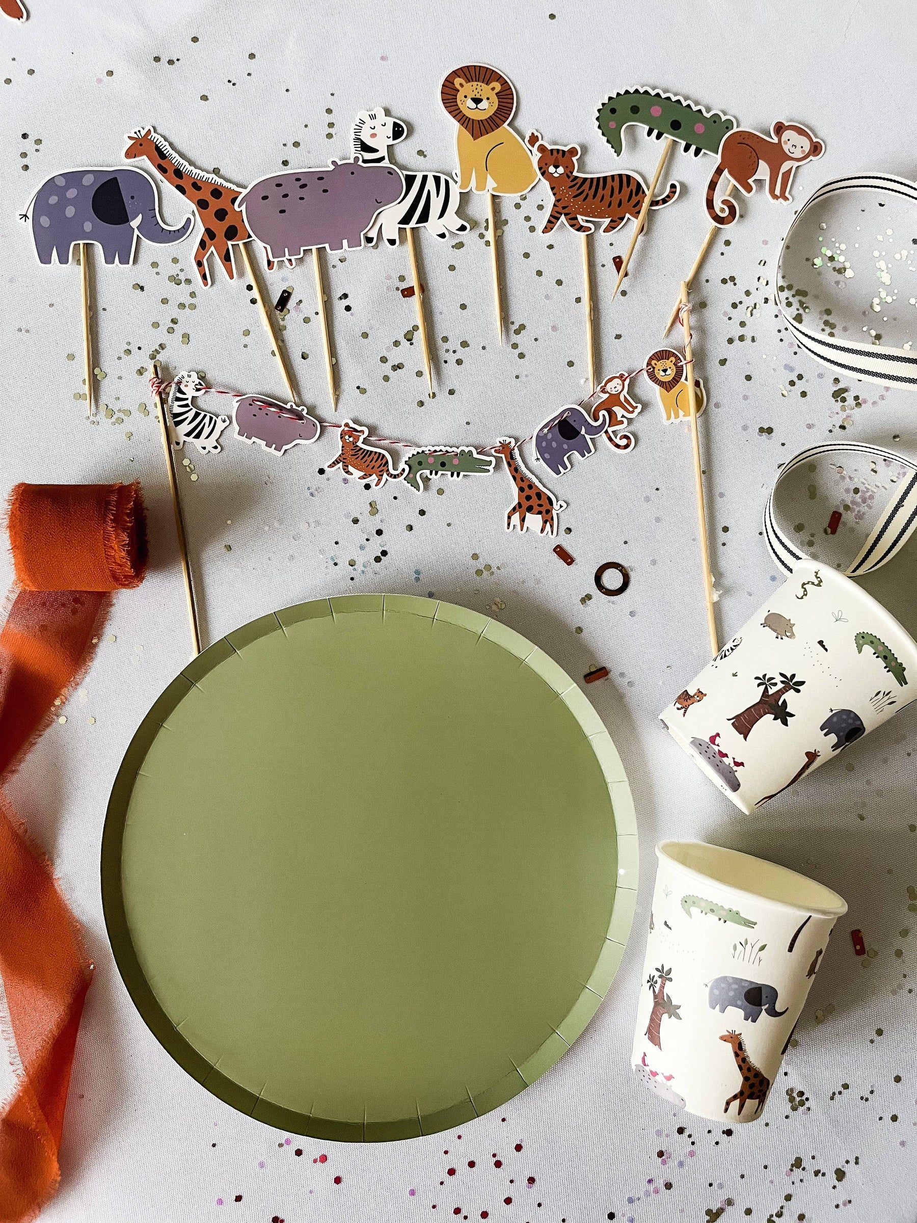Children's party supplies with animal-themed decorations on a white surface
